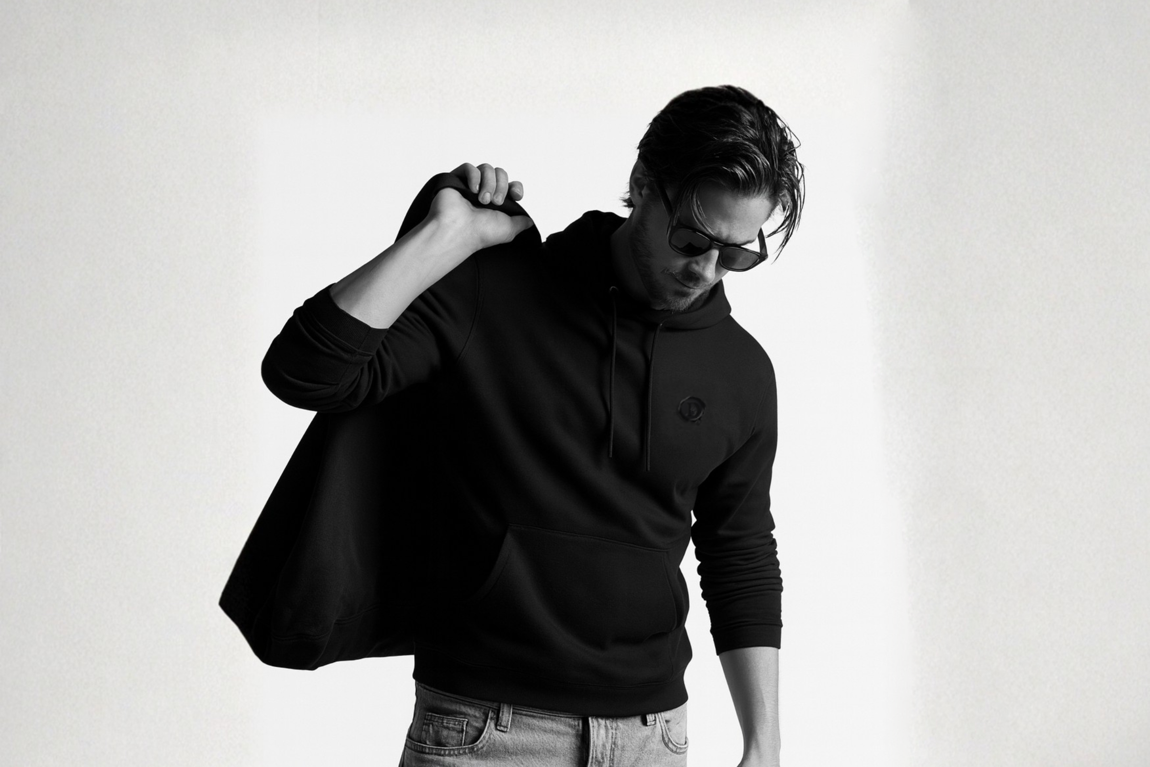 Person wearing black DISRPT hoodie with minimalist design in clean studio setting, modern streetwear aesthetic