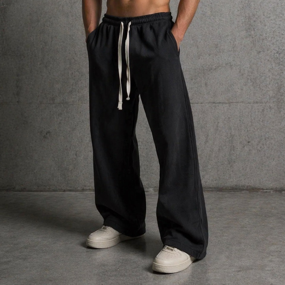 Front view of DISRPT black signature sweatpants showing relaxed fit, wide leg drape, and drawstring waist detail