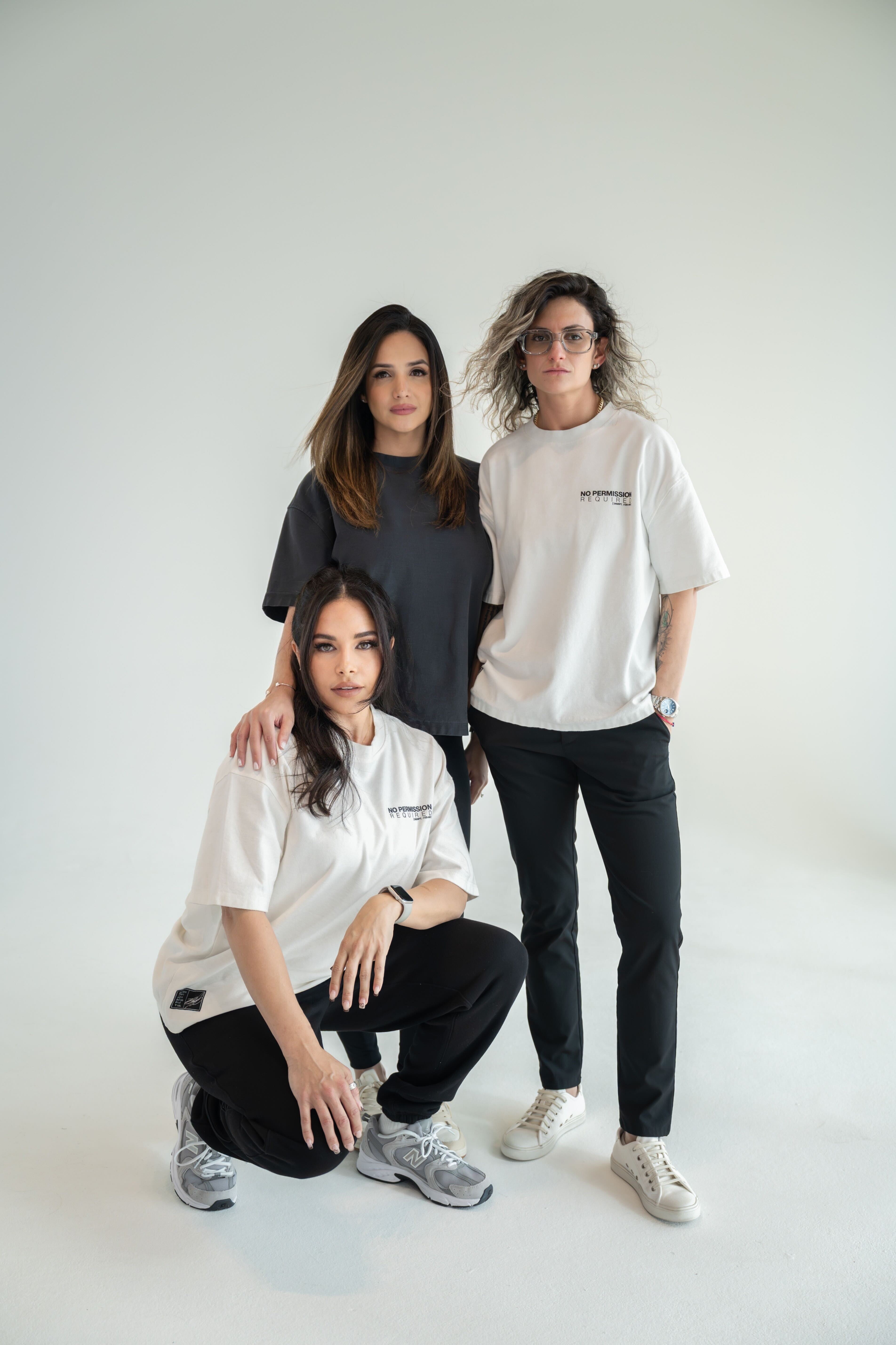 Women wearing DISRPT apparel styled in black and neutral tones posing as a minimal uniform in a clean studio