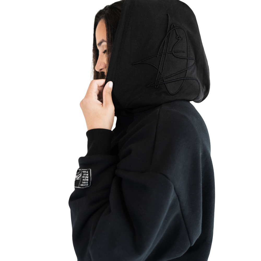 Person wearing black DISRPT signature heavyweight hoodie in side view on white background with minimalist design and relaxed fit