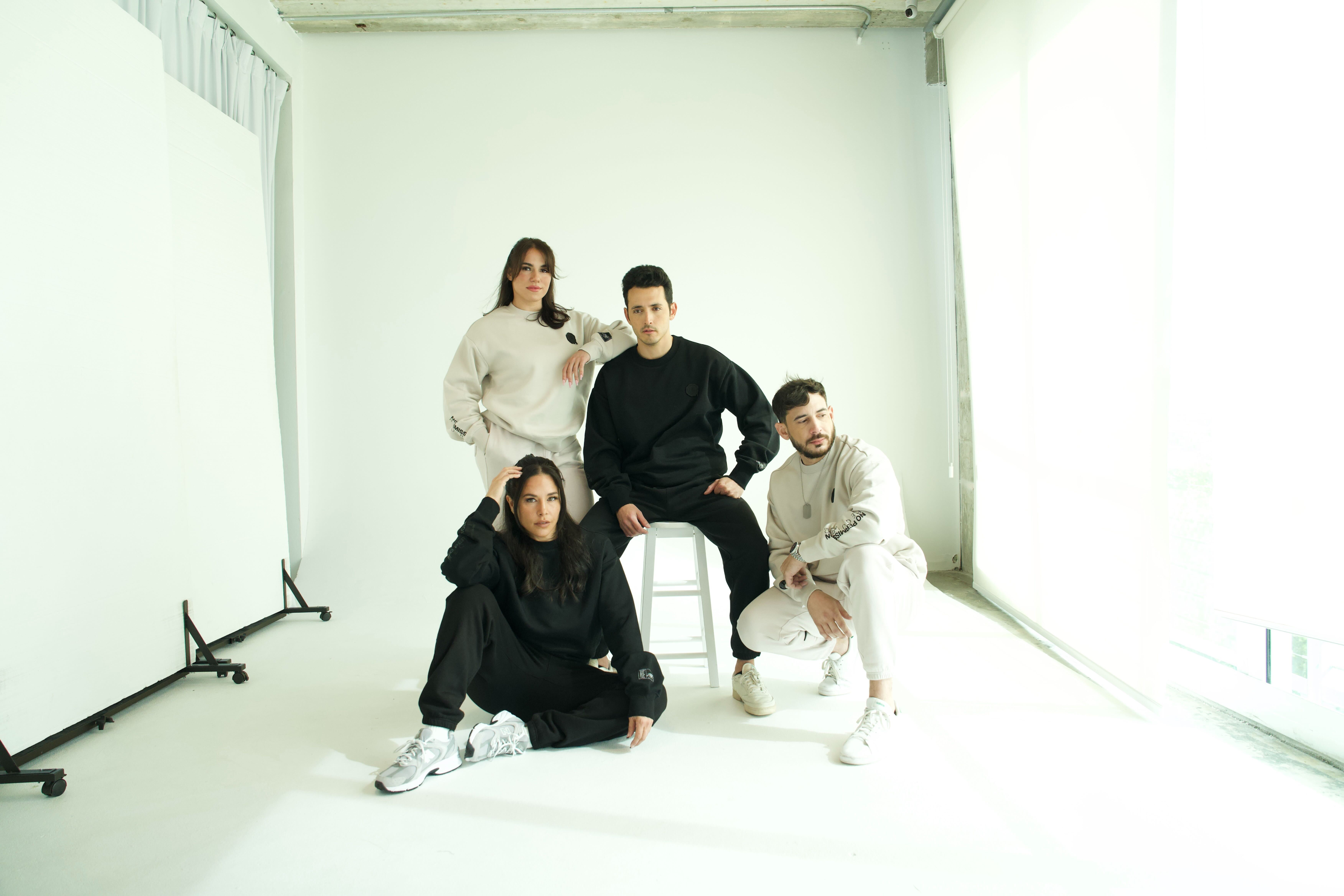 DISRPT team group portrait with four people in minimalist studio wearing neutral streetwear outfits