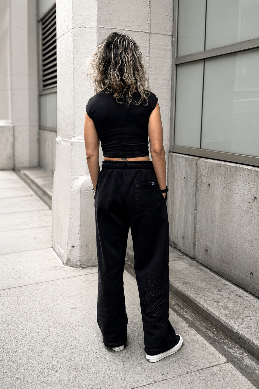 DISRPT black fitted tee back view worn in urban setting with relaxed wide leg pants