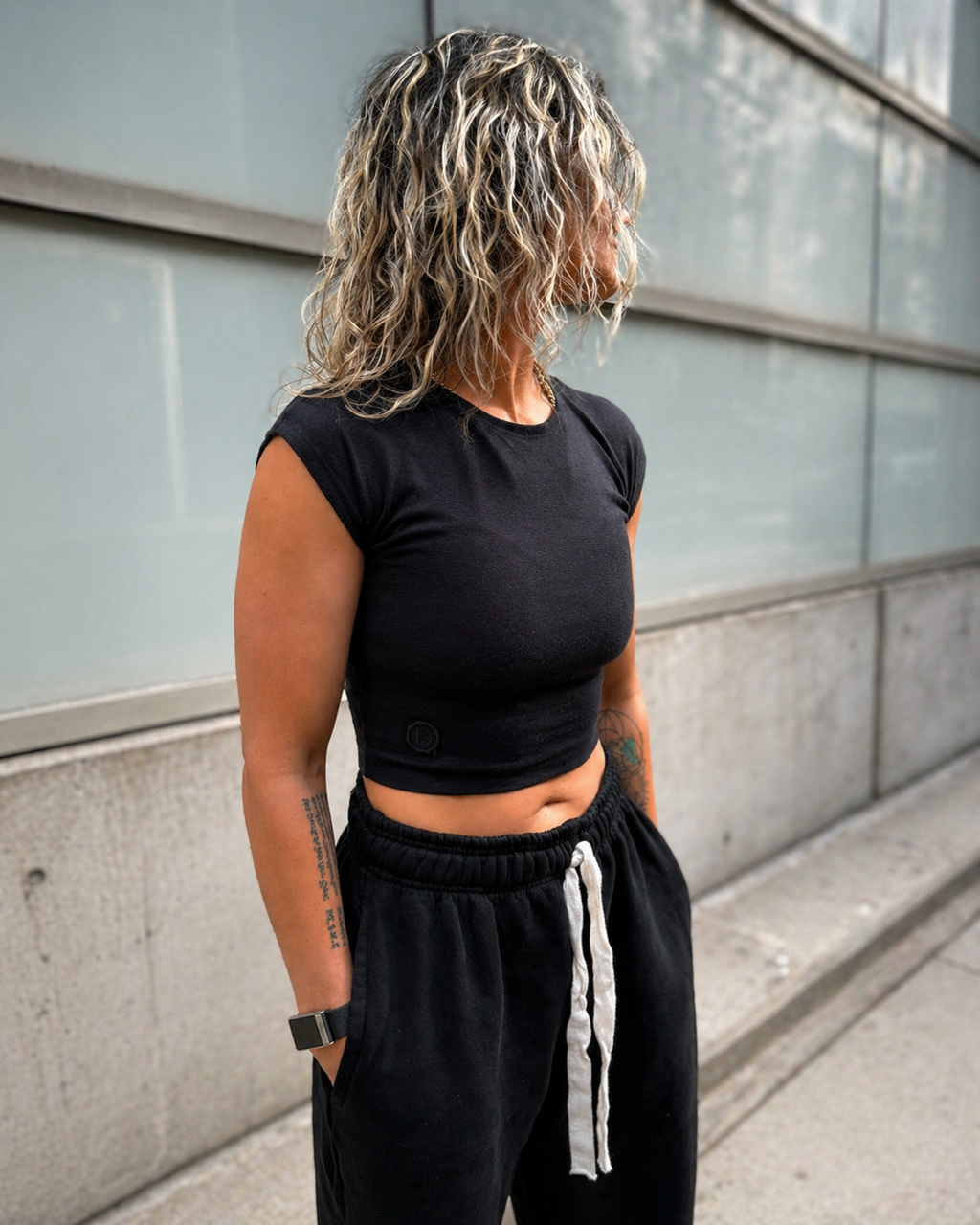 DISRPT black fitted tee worn in urban setting with relaxed black sweatpants side view